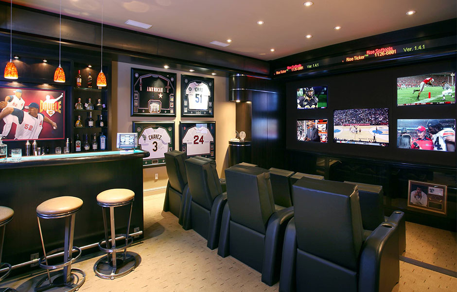 Sports themed man cave with memorabilia and multiple tv screens on the wall.